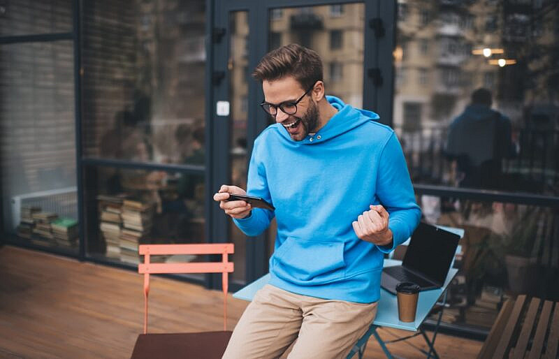 A man is celebrating after placing a successful bet online.